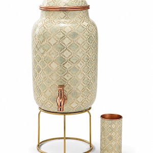 May include: A tall, cylindrical beverage dispenser with a light green and white quatrefoil pattern, featuring a copper-toned spigot, a matching lid with a gold knob, and a gold metal wire stand, accompanied by a matching cylindrical tumbler.