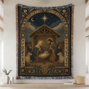 May include: A woven tapestry blanket featuring a nativity scene with a central manger, figures in robes, a donkey, a cow, and two sheep under a star-filled night sky. The rectangular design is framed by an ornate archway with floral motifs.