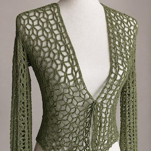 May include: An olive green long-sleeve cardigan featuring an open-knit crochet pattern with a geometric web-like design. The garment has a deep V-neckline and a single tie closure at the center front, constructed with a lightweight yarn texture.