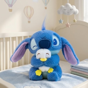 May include: A blue plush toy of a cartoon character with large ears and a winking expression, holding a smaller white and yellow plush toy. The plush toys are on a light blue blanket, with a crib and decorative hanging mobile in the background.