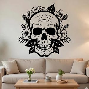 May include: Black and white skull wall art with floral detailing. The skull has detailed teeth and eye sockets, framed by stylized flowers and leaves. This gothic-inspired decor adds a unique touch to any room.