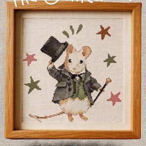 May include: Cross-stitch pattern of a mouse dressed in a suit and top hat, holding a cane. The mouse is surrounded by stars in a wooden frame. The text "The Gentlemouse" and "Cross Stitch Pattern" are displayed.