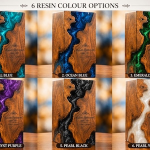 May include: Six rectangular wooden urns featuring a central river-like inlay of colored resin. The resin colors are teal blue, ocean blue, emerald green, amethyst purple, pearl black, and pearl white. Each urn displays the text Robert Thompson 1946-2023.