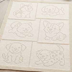 Puede incluir: Una manta de punto color crema con seis paneles cuadrados distintos, cada uno con una ilustración de cachorro diferente en contorno marrón claro. La manta tiene un borde texturizado y una apariencia tejida suave con varios perros.