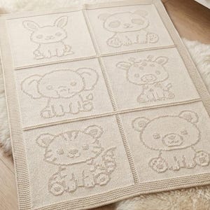 May include: A rectangular cream-coloured knit baby blanket featuring six distinct squares, each displaying a different embossed animal character including a rabbit, panda, elephant, giraffe, tiger, and bear, finished with a textured border.