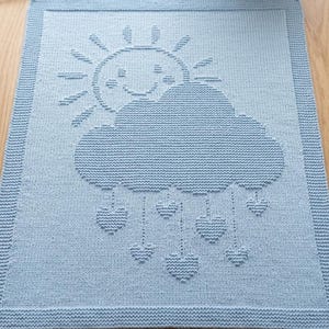 May include: A light blue rectangular knit blanket featuring a textured pattern of a smiling sun, a large cloud, and several heart-shaped raindrops hanging from the cloud. The blanket has a wide, textured border around the entire perimeter.