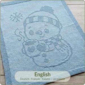 May include: A light blue knitted blanket featuring a textured pattern of a snowman wearing a hat and scarf, holding a mug with a heart design, accompanied by a snowflake. The text "English" is printed at the bottom of the image.