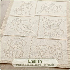 May include: A cream-colored knitted blanket featuring six distinct rectangular panels, each displaying a different puppy illustration in a subtle tonal stitch pattern. The blanket has a textured border and a repeating watermark text.