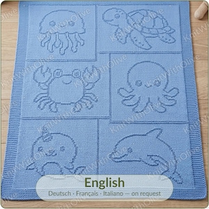 May include: A light blue knitted blanket featuring six distinct rectangular panels, each displaying a different marine animal outline including a jellyfish, turtle, crab, octopus, narwhal, and dolphin, with a textured border surrounding the design.