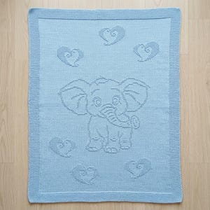 May include: A light blue knitted blanket featuring a textured elephant design in the center, surrounded by five heart motifs. The blanket has a wide, ribbed border that frames the central pattern, creating a consistent look across the entire piece.