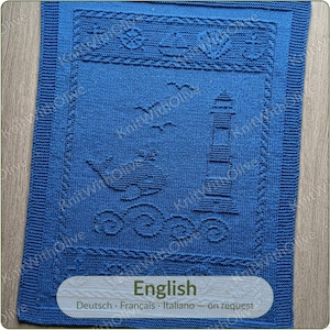 May include: A rectangular blue knitted blanket featuring a textured design of a lighthouse, a whale, and ocean waves. The border includes nautical motifs such as anchors, a ship's wheel, and a boat. The word English is printed at the bottom.
