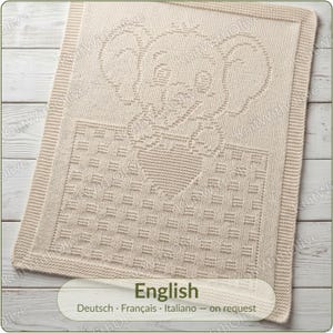 May include: A rectangular cream-coloured knitted blanket featuring a textured elephant design at the top and a woven basket-weave pattern at the bottom. The blanket has a simple garter stitch border framing the central graphic elements.