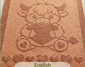 May include: A rectangular, terracotta-colored knitted blanket featuring a textured pattern of a central highland cow holding a heart, surrounded by smaller heart motifs. The bottom includes a label with the text English, Deutsch, Français, Italiano - on request.