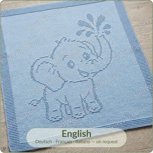 May include: A square light blue knitted blanket featuring a textured elephant design in the centre. The elephant is depicted with its trunk raised, spraying water. The blanket has a wide, ribbed border and includes the text KnitWithOlive.
