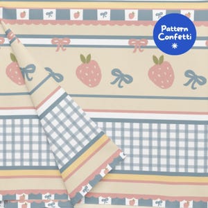 Può includere: Un tessuto con un motivo ripetuto di fragole rosa e fiocchi blu su sfondo beige, con strisce orizzontali e una sezione a quadretti vichy blu e bianchi. Un logo circolare blu nell'angolo riporta il testo Pattern Confetti.