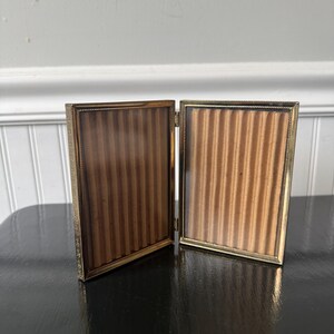 vintage gold-tone metal bi-fold picture frame designed to hold two 5x3.5 vertical photos