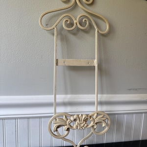 off-white wrought iron wall plate rack features ornate scrolling and floral details