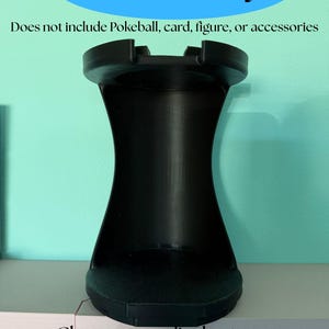 May include: A black display stand with a concave vertical body and a circular base. The text reads: Insert Only, Does not include Pokeball, card, figure, or accessories, Choose your display type: Figure, Slab, Graded Guard, Ultra Pro, 2026 Art of Stormes.
