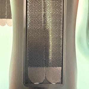 May include: A black plastic mount featuring a rectangular recessed area containing two vertical strips of black hook-and-loop fastener material. The fastener strips have rounded bottom edges and a dense, textured surface for secure attachment.