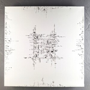 Op de afbeelding: Vierkant wit canvas met een zwart abstract ontwerp. Het kunstwerk heeft een centrale cluster van zwarte lijnen en vormen, met extra lijnen en markeringen rond de randen, waardoor een textuureffect ontstaat. De achtergrond is effen wit.