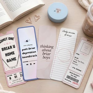 May include: A collection of decorative bookmarks and accessories, including a light blue container, a glass of iced coffee, and heart-shaped paper clips. The bookmarks feature text such as "BRIAR U HOME GAME" and "post-briar depression soundtrack."