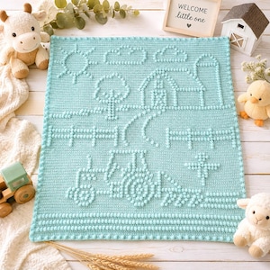 May include: A light blue crochet blanket featuring a textured bobble stitch design of a farm scene, including a tractor, a barn, a tree, clouds, and a sun. The blanket has a simple border and is crafted with a consistent stitch pattern throughout.