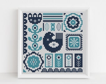 Op de afbeelding: Een ingelijst kruissteekpatroon met een geometrisch ontwerp in tinten blauw en wit. Het patroon bevat verschillende vormen, waaronder cirkels, vierkanten en sterren.