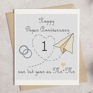 May include: A handmade cross-stitch anniversary card with the text "Happy Paper Anniversary" and "our 1st year as Mr + Mr". The card features a heart with the number 1, a paper airplane, and two interlocking circles.