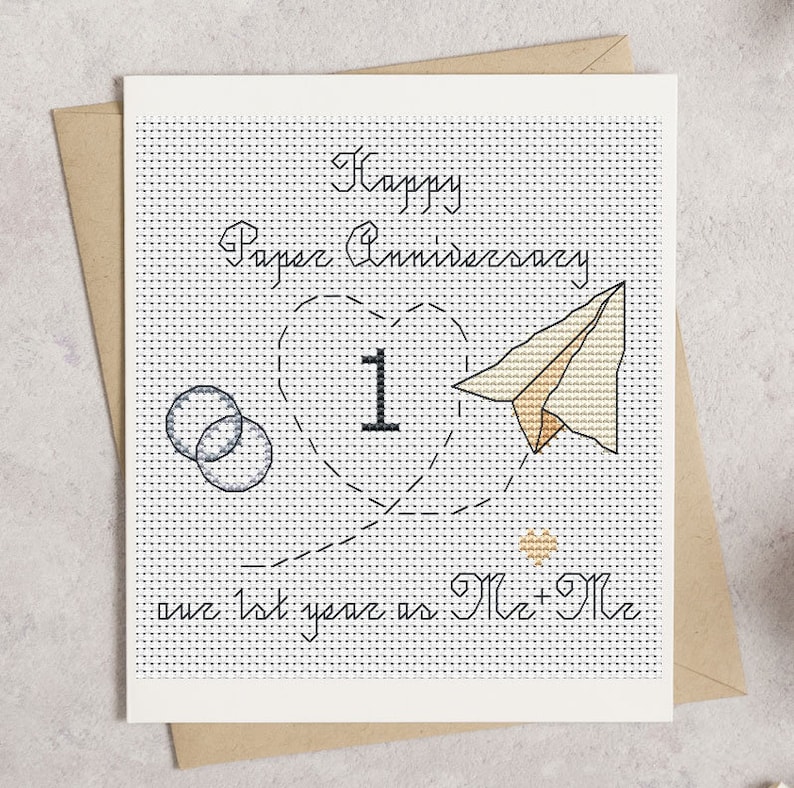 May include: A handmade cross-stitch anniversary card with the text "Happy Paper Anniversary" and "our 1st year as Mr + Mr". The card features a heart with the number 1, a paper airplane, and two interlocking circles.