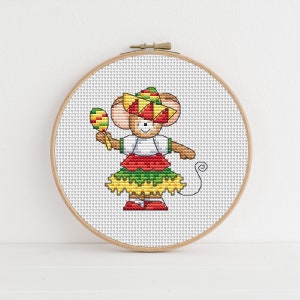 May include: A cross-stitch embroidery hoop with a colorful image of a mouse wearing a sombrero and holding a maraca. The mouse is wearing a red and green dress with a yellow skirt.