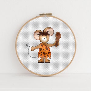 May include: A cross-stitch pattern of a cartoon mouse dressed as a caveman, holding a club. The mouse is brown with a tan face and is wearing a brown loincloth with a leopard print pattern.