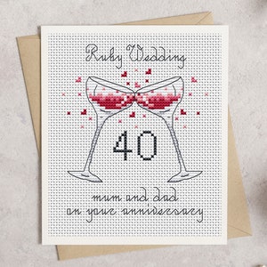May include: Cross-stitch Ruby Wedding anniversary card. Features two champagne glasses clinking, filled with red liquid, and the number 40. The text reads "Ruby Wedding" and "mum and dad on your anniversary". The card is on a white background.