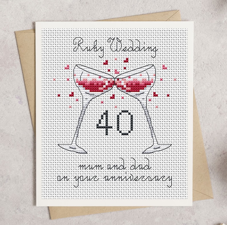May include: Cross-stitch Ruby Wedding anniversary card. Features two champagne glasses clinking, filled with red liquid, and the number 40. The text reads "Ruby Wedding" and "mum and dad on your anniversary". The card is on a white background.