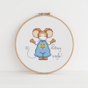 May include: Cross stitch pattern of a mouse wearing a face mask and a rainbow heart on its overalls. The text "Stay safe!" is stitched below the mouse.