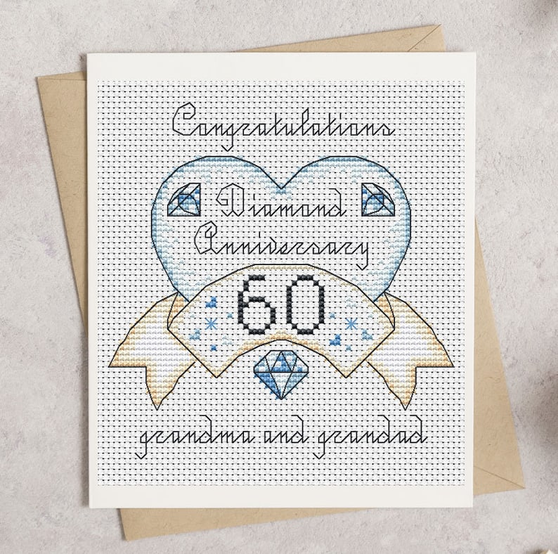 May include: A cross-stitch greeting card with a diamond anniversary theme. The card features a blue heart with the words "Diamond Anniversary 60" and "Congratulations grandma and grandad". The card is on a white background with a brown envelope.