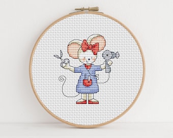 Peut inclure: Un cerceau de broderie en point de croix avec un fond blanc et une illustration colorée d'une souris tenant un sèche-cheveux et des ciseaux. La souris porte une robe bleue avec un nœud rouge et a un nez rose.