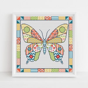 May include: A framed cross-stitch of a colorful butterfly. The butterfly has patterned wings in yellow, orange, red, blue, and green. The frame has a geometric border with similar colors. The artwork is displayed on a white surface.