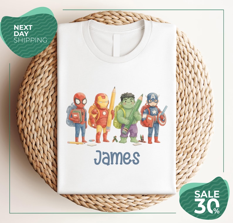 A white t-shirt with a printed design of four superhero characters, including Spider-Man, Iron Man, Captain America, and James, standing together.