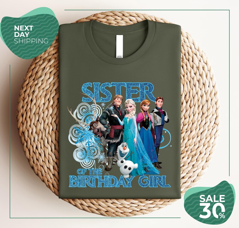 A green t-shirt with a graphic design featuring characters from the Disney movie Frozen, specifically the sisters Elsa, Anna, Olaf, and Olaf.