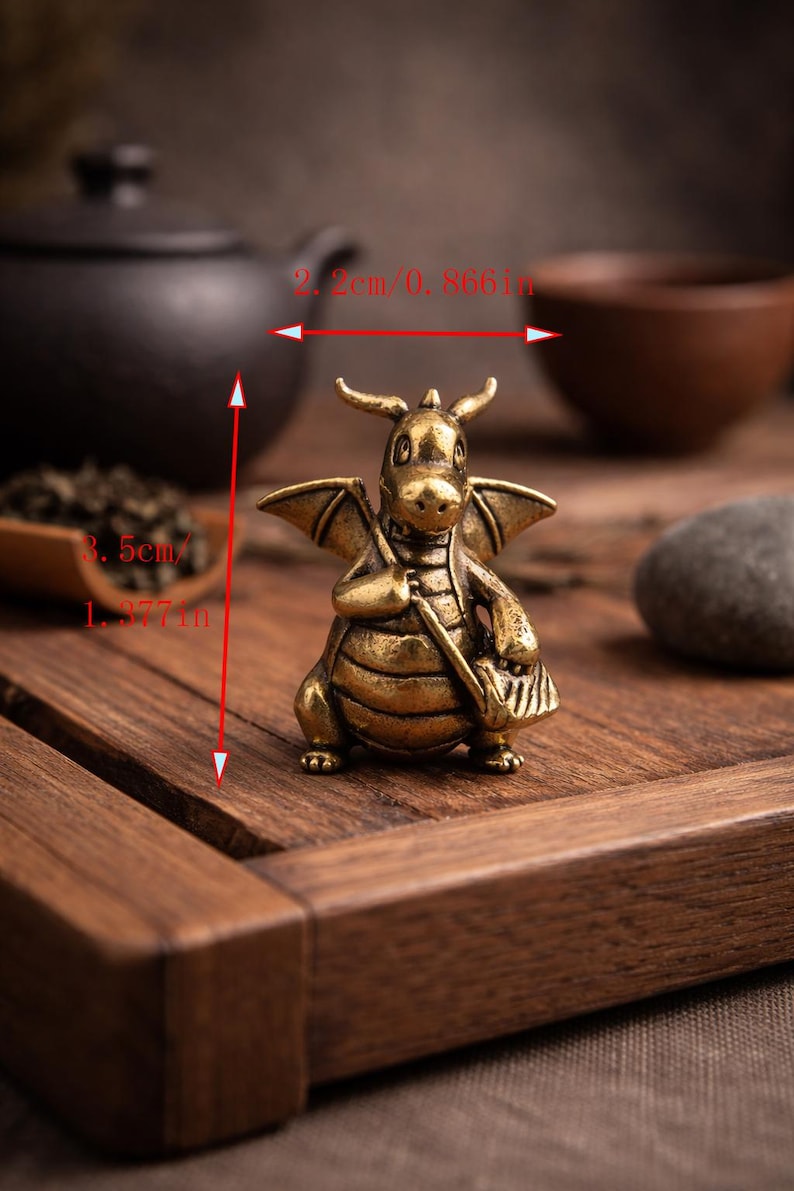 May include: A detailed brass dragon figurine, 1.377 inches tall and 0.866 inches wide, with horns, wings, and a satchel. The dragon is posed on a wooden surface, suggesting a decorative or collectible item.