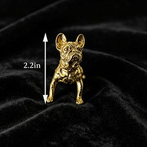 Peut inclure: Une figurine de bouledogue fran&ccedil;ais de couleur dor&eacute;e avec des traits du visage d&eacute;taill&eacute;s et un harnais, debout en position frontale. Une fl&egrave;che de mesure verticale indique une hauteur totale de 5,6 cm pour cette petite sculpture en m&eacute;tal.
