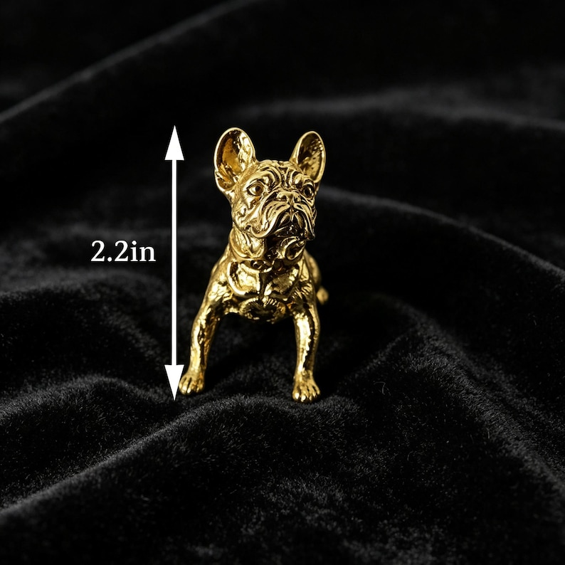 Peut inclure: Une figurine de bouledogue fran&ccedil;ais de couleur dor&eacute;e avec des traits du visage d&eacute;taill&eacute;s et un harnais, debout en position frontale. Une fl&egrave;che de mesure verticale indique une hauteur totale de 5,6 cm pour cette petite sculpture en m&eacute;tal.