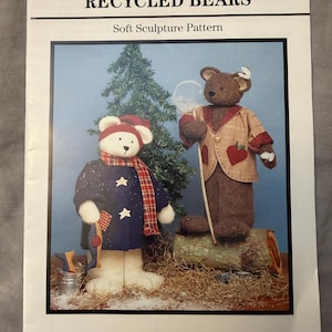 May include: Fabricraft pattern for Recycled Bears. The image shows two soft sculpture bears, one wearing a navy blue coat with star accents and a red and black scarf, and the other in a tan jacket with red heart details. The text reads "Transform a Recycled Plastic Bottle into a Bear."