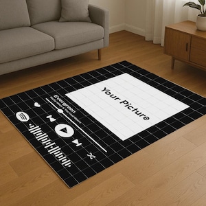 Op de afbeelding: Zwart-wit vloerkleed met een ontwerp van een muziekspelerinterface. Het vloerkleed heeft een rasterpatroon, een witte rechthoek met de tekst "Your Picture" en een bedieningspaneel van de muziekspeler met het woord "Evergreen".