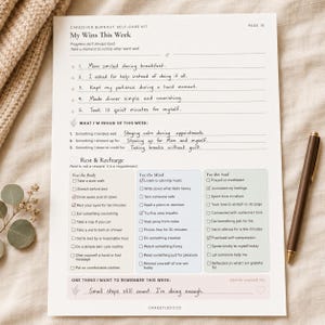My Wins This Week caregiver self-care worksheet filled with handwritten reflections and checked rest activities on soft beige fabric with a pen and dried flowers.