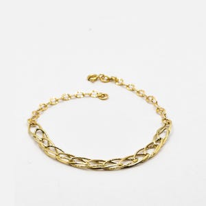 Puede incluir: Una pulsera dorada con un delicado diseño de cadena. La pulsera presenta una serie de eslabones ovalados y circulares interconectados, creando un accesorio elegante. El cierre es visible y la pulsera está sobre un fondo blanco.