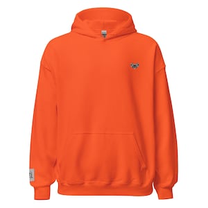 Puede incluir: Sudadera con capucha de color naranja brillante con bolsillo delantero y capucha. Un pequeño diseño bordado está en la parte superior izquierda del pecho. El puño de la manga tiene una pequeña etiqueta cuadrada con un gráfico. La sudadera con capucha está hecha de un material suave.