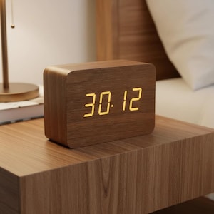May include: A wooden digital clock displaying the time 30:12. The clock has a rectangular shape with rounded edges and a wood grain finish. The numbers are illuminated in a warm yellow color.
