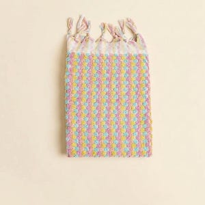 Può includere: Un asciugamano rettangolare dai colori pastello con un motivo strutturato. L'asciugamano presenta un motivo ripetuto di punti rosa, gialli e blu. Il bordo superiore ha nappe annodate nei colori coordinati. L'asciugamano è lungo circa 61 cm.