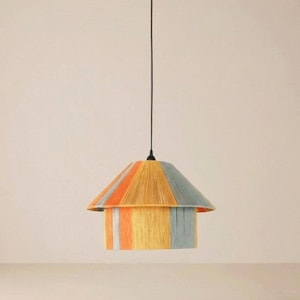 Può includere: Una lampada a sospensione colorata con un design a righe. Il paralume presenta strisce verticali arancioni, gialle e blu. La luce è appesa a un cavo nero su uno sfondo neutro. Questo apparecchio decorativo aggiunge un tocco di colore.